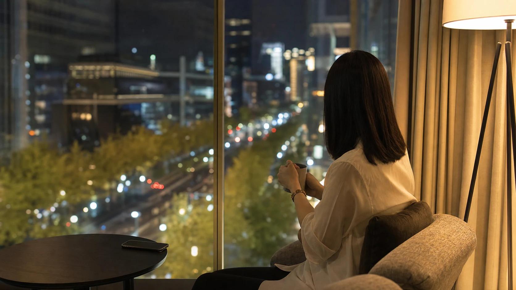 心斎橋のホテルラウンジで御堂筋の夜景を眺める日本人女性